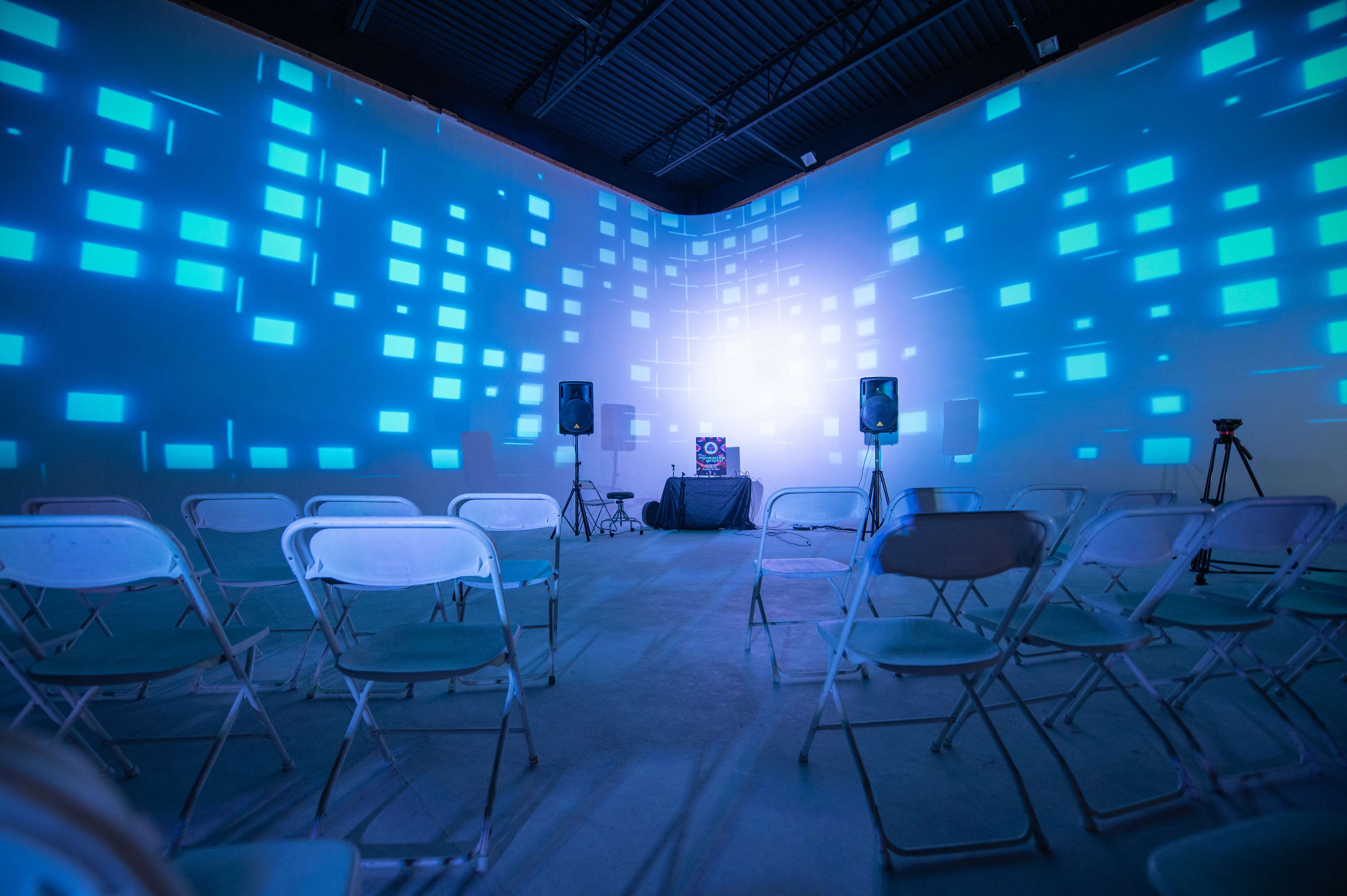 Studio space with blue geometric light projections on walls and seating